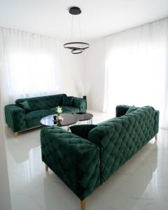 una sala de estar con 2 sofás verdes y una mesa. en Villa Domino, en Mostar