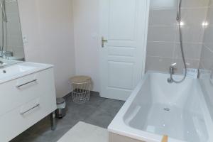 un bagno bianco con vasca e lavandino di Gite Les Promenades a Bellême