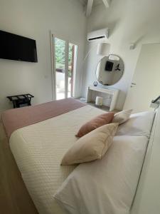 a white bedroom with a large bed with pillows at Martanna Rooms in Carini