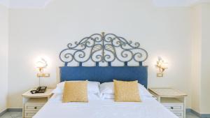 a bedroom with a large bed with a blue headboard at Hotel Nettuno in Ischia