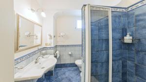 a blue tiled bathroom with a sink and a toilet at Hotel Nettuno in Ischia
