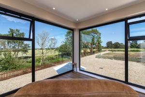 Schlafzimmer mit großen Fenstern und Blick auf einen Hof in der Unterkunft Scenic, Getaway Lux House in Countryside Village in Beccles
