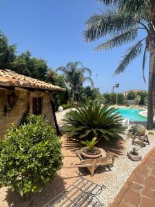 a resort yard with a swimming pool and palm trees at Martanna Rooms in Carini