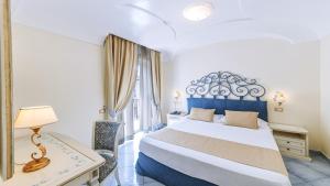 a hotel room with a bed and a desk and a window at Hotel Nettuno in Ischia