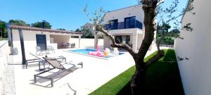 una casa con piscina e albero di Villa Salvore - new luxury house, heated pool, near beaches, playroom - Istria a Savudrija