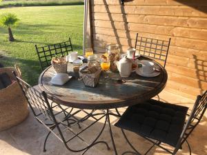una mesa de madera con comida y bebida en el patio en Jolie chambre d'hôtes au calme, en Oisly