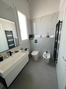 a white bathroom with a sink and a toilet at Martanna Rooms in Carini