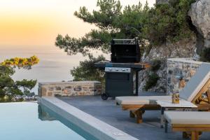 a grill on a patio next to a table and benches at Villa K-Villa with private pool in Ierápetra