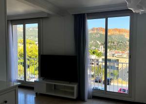 sala de estar con TV de pantalla plana y ventanas grandes. en La Cigale du Port en Cassis