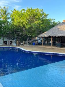 a large blue swimming pool with a thatch roof at Bangalôs da Barra Chalé 3 in Barra Grande