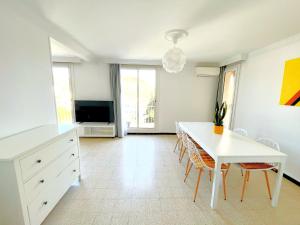 a living room with a white table and a tv at La Cigale du Port in Cassis