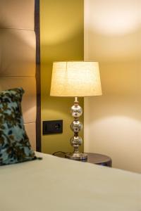 a lamp on a table next to a bed with a pillow at Hôtel Des Gouverneurs in Bastia