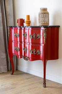 a red chest of drawers with embroidery on it at Hôtel Des Gouverneurs in Bastia
