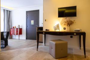 a room with a desk with a television on a wall at Hôtel Des Gouverneurs in Bastia