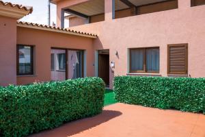 a house with green hedge in front of a building at Mare Sole in San Teodoro