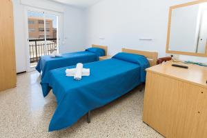 a room with two beds with blue sheets and a cross on it at Hostal El Mercat in Villajoyosa