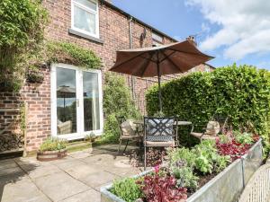 patio con tavolo, ombrellone e fiori di Lucky Cottage a Foxt