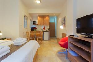 a room with a bed and a television and a kitchen at Colony Suites- Hananya St. in Jerusalem