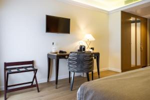 a hotel room with a desk with a bed and a television at Hôtel Des Gouverneurs in Bastia