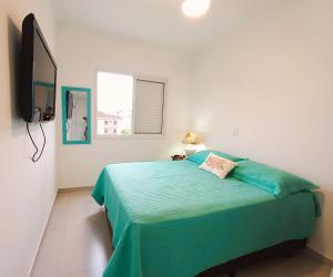 a bedroom with a green bed with a window at 500 metros da Orla Itaguá em Ubatuba - Varanda Gourmet/ Wi-fi in Ubatuba +29 photos