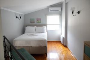 1 dormitorio con cama blanca y ventana en Minimal loft at Kastellokampos en Patras