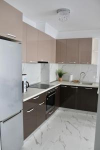 a kitchen with brown cabinets and white marble floors at Luxe Central Apt: Free Parking in Oradea