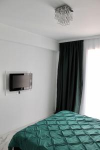 a bedroom with a green bed and a chandelier at Luxe Central Apt: Free Parking in Oradea