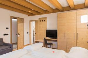 um quarto com uma cama, uma secretária e uma televisão em Baita Boniprati em Daone
