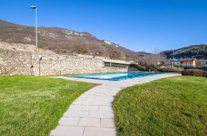 - une piscine à côté d'un mur en pierre et d'herbe dans l'établissement Villa Bevilacqua Nuovo bilocale modernopiscina, à Caprino Veronese