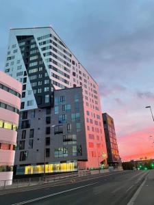 a tall building on a city street with a sunset at Tampere Kannen Topaasi - Apartment by the Nokia Arena in Tampere