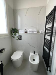 a white bathroom with a toilet and a sink at Martanna Rooms in Carini