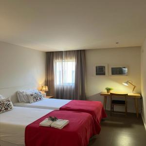 1 Schlafzimmer mit 2 Betten mit roter Bettwäsche und einem Schreibtisch in der Unterkunft bnapartments Palacio in Porto