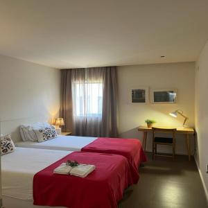 1 dormitorio con 2 camas con sábanas rojas y escritorio en bnapartments Palacio en Oporto