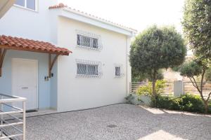 una casa blanca con una puerta blanca y un árbol en Minimal loft at Kastellokampos en Patras