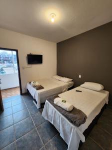 a room with two beds and a flat screen tv at Lofts Visconde in Joinville