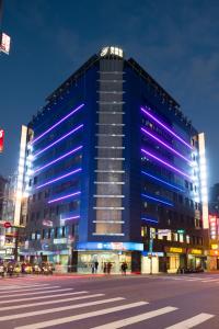 台北的住宿－洛碁大飯店驛館，一座蓝色的大建筑,上面有紫色的灯