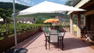 einen Tisch und Stühle unter einem Sonnenschirm auf einer Terrasse in der Unterkunft Gite Chez Jean in Saint-Hippolyte