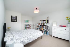 a bedroom with a bed and a dresser and book shelves at Beautiful 4BR Home in Vibrant Haringey in London