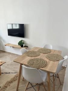 a wooden table with white chairs and a television at Emplacement idéal : Appartement lumineux El Jadida in El Jadida