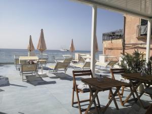 patio ze stołami i krzesłami oraz oceanem w obiekcie Tulla's w mieście Giardini Naxos