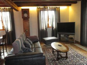 a living room with a couch and a table and a television at Gite Chez Jean in Saint-Hippolyte