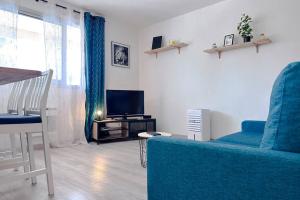 uma sala de estar com um sofá azul e uma televisão em DECAROLI - Stylish and Central Renovated Modern Studio em Saint-Laurent-du-Var