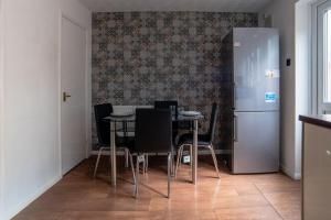 a dining room with a table and chairs and a refrigerator at Cheerful 3 Bedroom Family Home with parking in Leicester