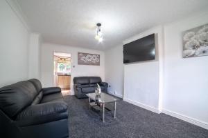 een woonkamer met een zwarte leren bank en een tafel bij Cheerful 3 Bedroom Family Home with parking in Leicester