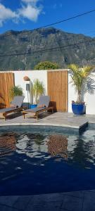 una piscina con 2 tumbonas junto a una casa en Villa Ananda, en Cilaos