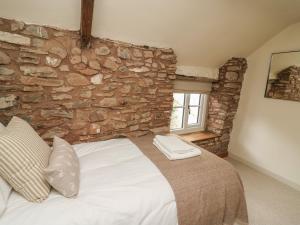 a bedroom with a stone wall with a bed and a window at Groveside in Hereford