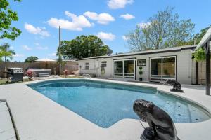 una piscina con una estatua junto a una casa en Perfect Pool & Hot Tub Retreat, en Pinellas Park