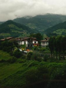 een groep huizen op een heuvel met bergen bij Baiolei in Azpeitia