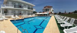 a swimming pool with white chairs and a building at Athina Studios in Argasi