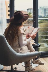 uma rapariga sentada numa cadeira a ler um livro em Neighbourgood Newlands na Cidade do Cabo